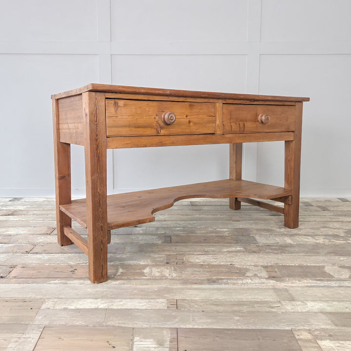 A 19th century Victorian pine console table originally designed as a farmhouse prep table, built in solid pine with a planked top, two drawers and a lower shaped shelf. This antique pine table with chunky straight legs is versatile in use, working as a serving table in the kitchen, a sideboard in a dining room or as a hallway console. Combining practical storage with generous surface space, it is a fine example of Victorian country furniture.