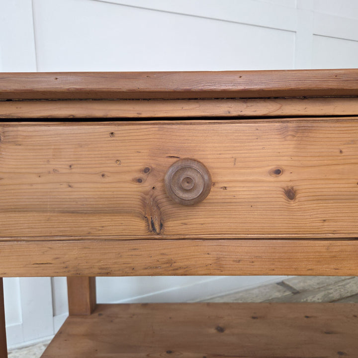 An antique pine farmhouse table from the 19th century Victorian period with planked top, two drawers and a lower shaped shelf. Raised on chunky straight legs, this versatile piece serves as a prep table in the kitchen, a sideboard in a dining space or as a console in a hallway. A fine example of Victorian farmhouse furniture, offering surface space and storage in a simple, functional design.