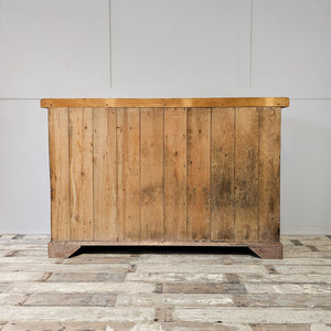 A rustic pine 19th-century kitchen dresser with a later scrubbed top, seven drawers and three cupboards. Brass swan-neck handles and round knobs give the piece a simple cottage style finish suited to organised storage around the home.