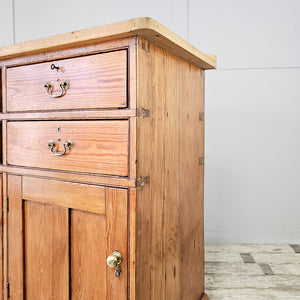 A large rustic pine kitchen dresser with a scrubbed top and cleated ends, featuring seven drawers and three cupboards. Matching brass handles and knobs complete this 19th-century sideboard for organised household storage.