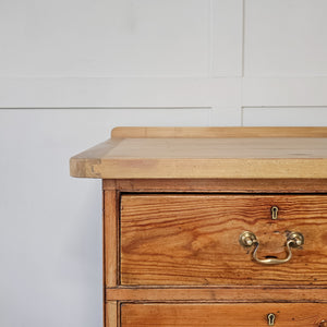 A farmhouse style pine sideboard from the 19th century with seven drawers, three cupboards and brass swan-neck handles. The lighter scrubbed top provides contrast, making this a versatile rustic pine storage piece.