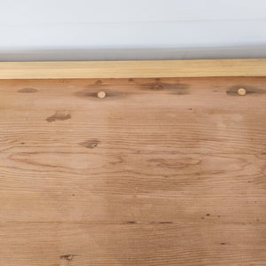 A rustic pine 19th-century kitchen dresser base offering seven drawers, three cupboards and matching brass fittings. The scrubbed pine top with cleated ends introduces a softer tone above the deeper country house style base.