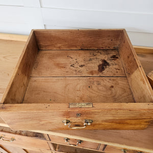 A cottage style pine sideboard from the 19th century, featuring seven drawers, three cupboards and brass hardware. The later scrubbed pine top with cleated ends complements the rustic base and provides generous storage options.