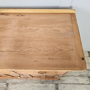 A 19th-century cottage style dresser base in pine, fitted with seven drawers and three cupboards with brass handles. The lighter scrubbed top provides a useful surface above generous storage.