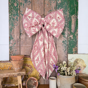 Decorative Country House Bow handmade from sourced vintage fabric, featuring a structured, padded design and tapering tails. Complete with a brass hanging ring, it’s a beautiful piece of home décor for dressing bedroom doors, mantels, or hallway hooks.