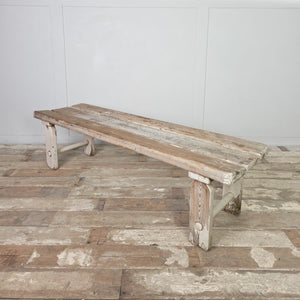 An early 1900s rustic country pine bench with three planks forming the seat and straight legs joined by circular lower stretchers. This farmhouse bench can be used as hallway seating, positioned at the foot of a bed, or used as a dining bench in a kitchen.