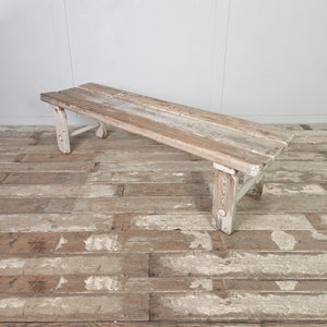 An early 20th-century farmhouse pine bench with a three-plank top and straight legs with circular lower stretchers. This practical bench can be used in a boot room or hallway, placed at the foot of a bed, or used as a dining bench.