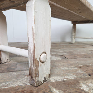 An antique pine bench dating from the early 20th century, constructed with a three-plank top and straight legs with circular lower stretchers. This farmhouse bench works well in a hallway or boot room and can also be used as a kitchen dining bench.