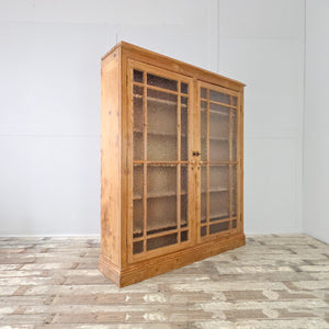 An early 20th century pine cupboard with tall glazed doors fitted with frosted glass, opening to adjustable shelving throughout. Finished with a waxed finish, this large rustic cupboard works well as general storage and has a relaxed farmhouse look.