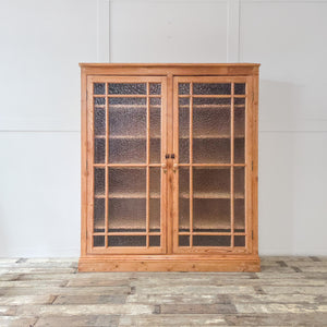 A substantial antique pine glazed cupboard dating from the early 20th century, built with two full-length glazed doors and adjustable shelving inside. Sealed in a clear furniture wax, this farmhouse cupboard is both practical and full of rustic appeal.