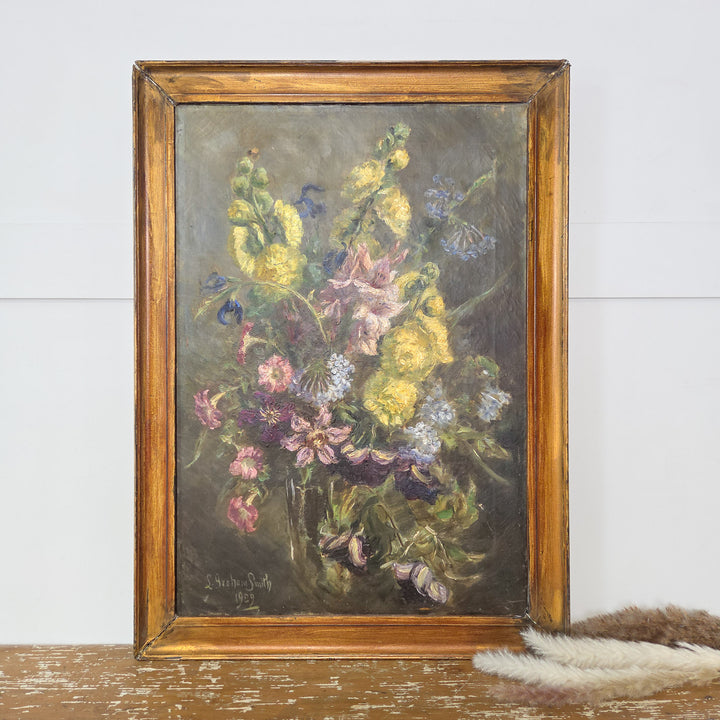 Antique floral oil painting signed by Canadian impressionist L Graham Smith, dated 1929. Features a colourful collection of garden flowers painted in oil on canvas, set within a simple painted gilt frame. An original early 20th-century artwork.
