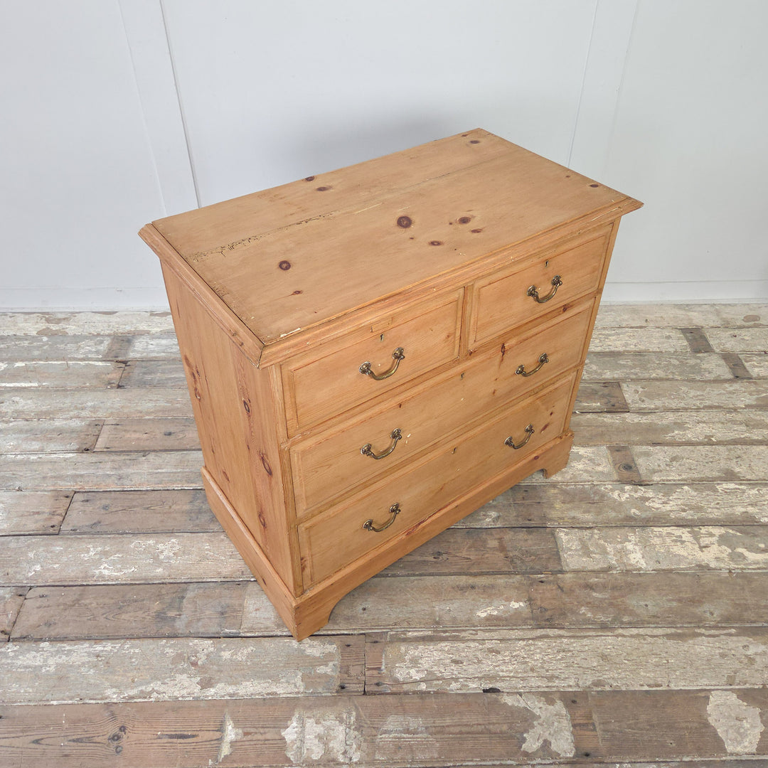 Early 20th century antique pine chest of drawers with four drawers, arranged as two short drawers over two long drawers. Retains original brass swan neck handles and escutcheons. Finished with a natural pine patina, plinth base, and moulded edges to the top, making a practical and attractive bedroom storage option.