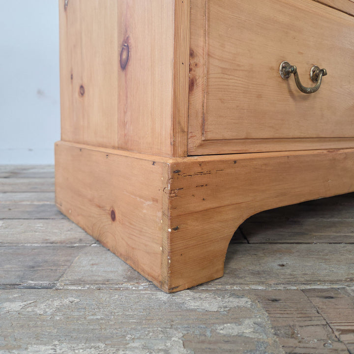 Antique pine chest of drawers, early 20th century, featuring two short drawers above two longer drawers. Retains original brass swan neck handles and escutcheons. Finished with a natural pine patina, sealed in wax, with a plinth base featuring decorative cut-out and moulded top edges. A functional storage piece.
