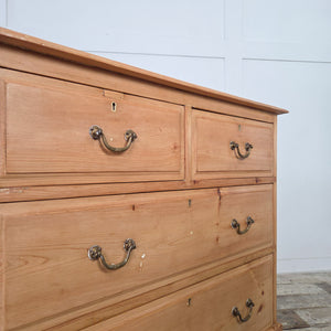 A well-proportioned early 20th century antique pine chest of drawers with four drawers, original brass handles, and escutcheons. The chest shows a natural pine patina, enhanced with clear wax. It sits on a plinth base with decorative cut-out to the front and is finished with moulded edges to the top.
