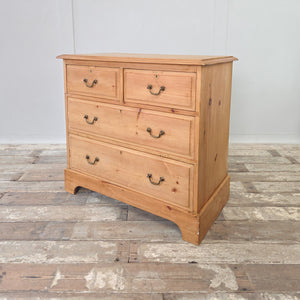 Early 20th century antique pine chest of drawers with four drawers in a two over two layout. Original brass handles, plinth base, and natural pine patina.