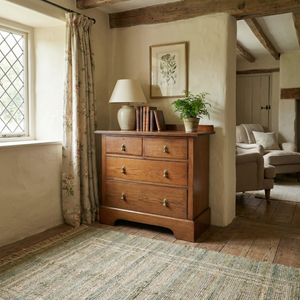 Edwardian antique oak chest of drawers from the early 20th century with four drawers in a two short over two long layout, decorative brass drop handles, moulded top edges and a shaped plinth base.

