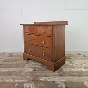 Edwardian antique oak chest of drawers showing a two short over two long drawer configuration, decorative brass drop handles, moulded top edges and a shaped plinth base.
