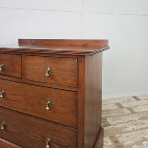 Antique oak chest of drawers dating to the Edwardian period, with four drawers, brass pear-drop handles, moulded top edging with a raised upstand and a shaped plinth base.
