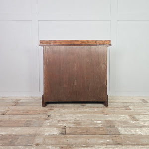 Antique oak chest of drawers from the Edwardian era, with four drawers, brass drop handles, moulded edges to the top with a small raised upstand and a plinth base.
