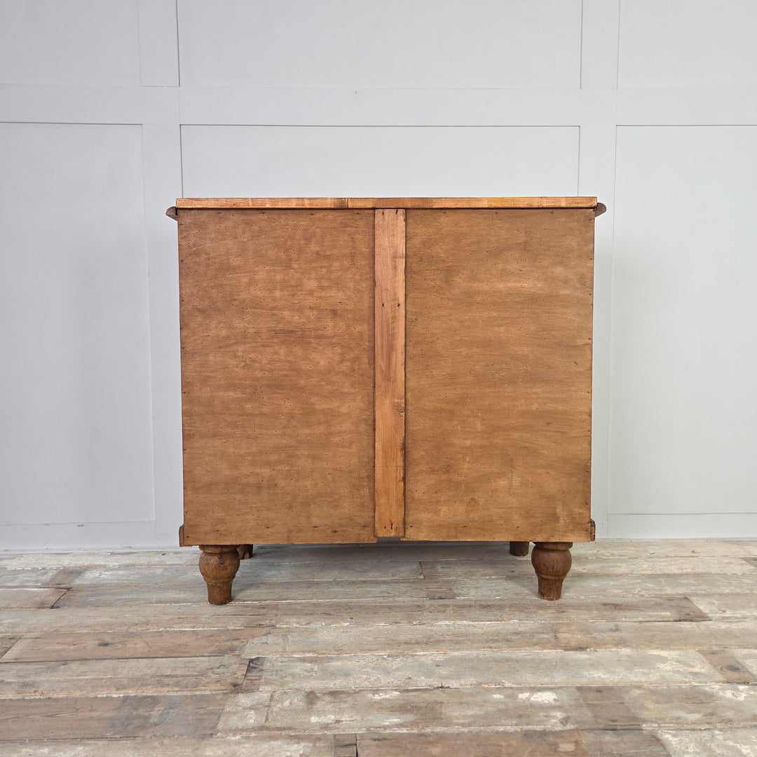 A country-style Edwardian satinwood storage chest with four drawers, reeded detailing and brass swing handles, standing on tulip-shaped feet and finished in Rustic Pine wax, highlighting the natural tone and depth of the satinwood.