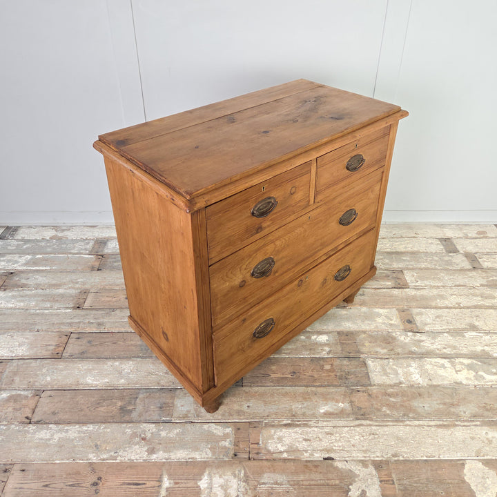A farmhouse satinwood storage chest dating from the Edwardian era, with four drawers in a two-over-two layout, reeded fronts and brass swing handles, raised on tulip-shaped feet and finished in Rustic Pine wax for a rich, natural look.