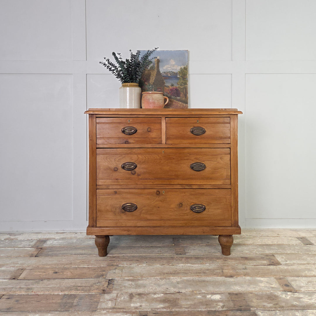 Edwardian satinwood chest of drawers offering functional storage across four drawers, each with reeded fronts and brass swing handles, standing on tulip-shaped feet and sealed in Briwax Rustic Pine for depth and protection.