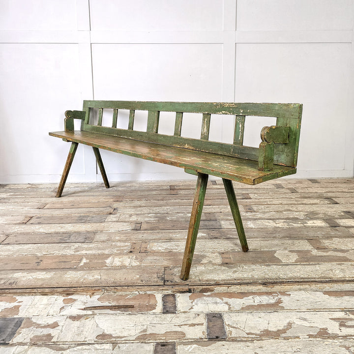 Green pine bench with stick legs and traditional form
