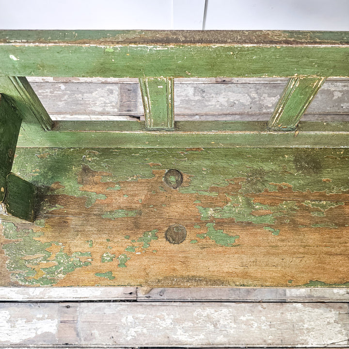 Green pine bench with stick legs and traditional form
