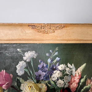 Vintage mid 20th century floral still life oil painting on board featuring a decorative vase of flowers in radiant pinks and yellows, contrasted against a dark ground. Framed within a complementary painted frame, this signed work captures a traditional subject for wall displa