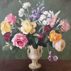 A 20th century floral still life oil painting on board, signed and framed, featuring pink and yellow flowers in a decorative vase. The blooms are arranged against a dark ground, creating definition and clarity, with the painted wooden frame completing the composition for wall display.
