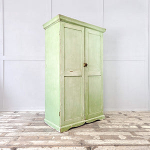 An early 20th-century French cupboard finished in soft green paint with two doors revealing eight graduated drawers with slatted bases. The shaped plinth and cornice enhance its farmhouse and country feel, making this antique painted cupboard a practical storage piece with strong character.