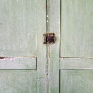 A French green painted cupboard from the early 1900s, retaining its original surface and opening to eight internal drawers with slatted bases. The shaped plinth and cornice emphasise its country and cottage style character, making this antique storage piece both functional and distinctive.