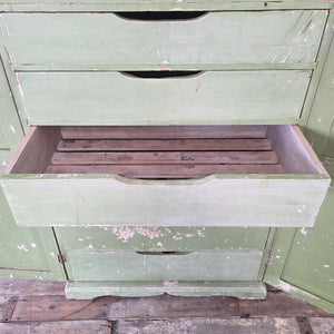Early 20th-century French cupboard in its worn soft green paint, fitted with two doors and eight internal drawers that vary in depth. Slatted bases suggest former use for dry goods. With its shaped plinth and cornice, this antique painted storage cupboard reflects classic French country design.