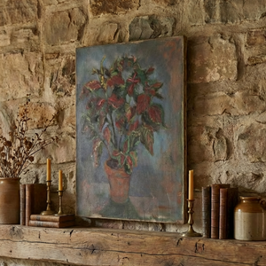 Decorative mantel with a painting, candles, and books against a stone wall.