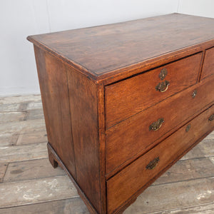 A classic Georgian oak chest of drawers from the early 19th century, with four drawers, brass handles and bracket feet. A useful antique storage piece with a rich oak tone.
