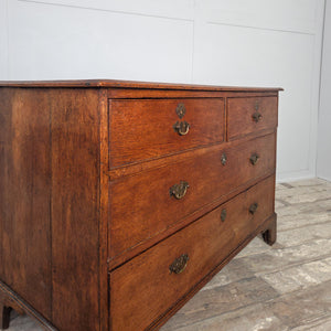 Antique early 19th century Georgian oak chest featuring four drawers, decorative bracket feet and original brass fittings. The oak has aged gracefully, showing a soft, even patina.