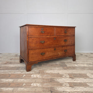 Georgian oak chest of drawers dating from the early 1800s, raised on decorative bracket feet with four drawers and original brass swan-neck handles. The oak has developed a deep, mellow patina through years of use.