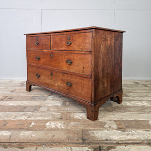 Early 19th century Georgian oak chest with four drawers, arranged in a traditional two-over-two format with brass fittings and bracket feet. The rich oak patina and gentle wear give this antique chest warmth and character.