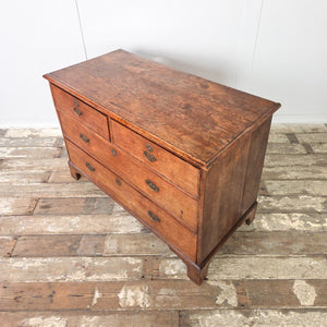Antique Georgian oak chest of drawers with four drawers, brass handles and escutcheons, raised on decorative bracket feet. The oak has a soft sheen and warm tone consistent with well-aged Georgian furniture.