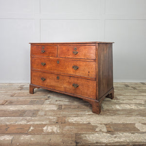 Antique Georgian oak chest of drawers from the early 19th century with two smaller drawers over two larger drawers, original brass handles and escutcheons, and shaped bracket feet. The oak surface shows a lovely depth of tone developed over time.