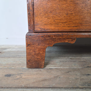 Georgian period oak chest of drawers from the early 19th century, with four drawers, brass swan-neck handles and escutcheons, and decorative bracket feet. A practical, well-proportioned antique storage piece.