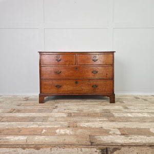 Early 19th century Georgian oak chest with four drawers in a two-over-two arrangement, original brass fittings and bracket feet. The oak surface shows even wear and a beautiful depth of colour.