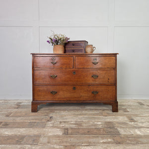 A fine early 19th century Georgian oak chest of drawers featuring four drawers, original brass fittings and decorative bracket feet. The oak has aged beautifully, displaying a rich warm patina. A quality antique chest offering useful storage across the home.