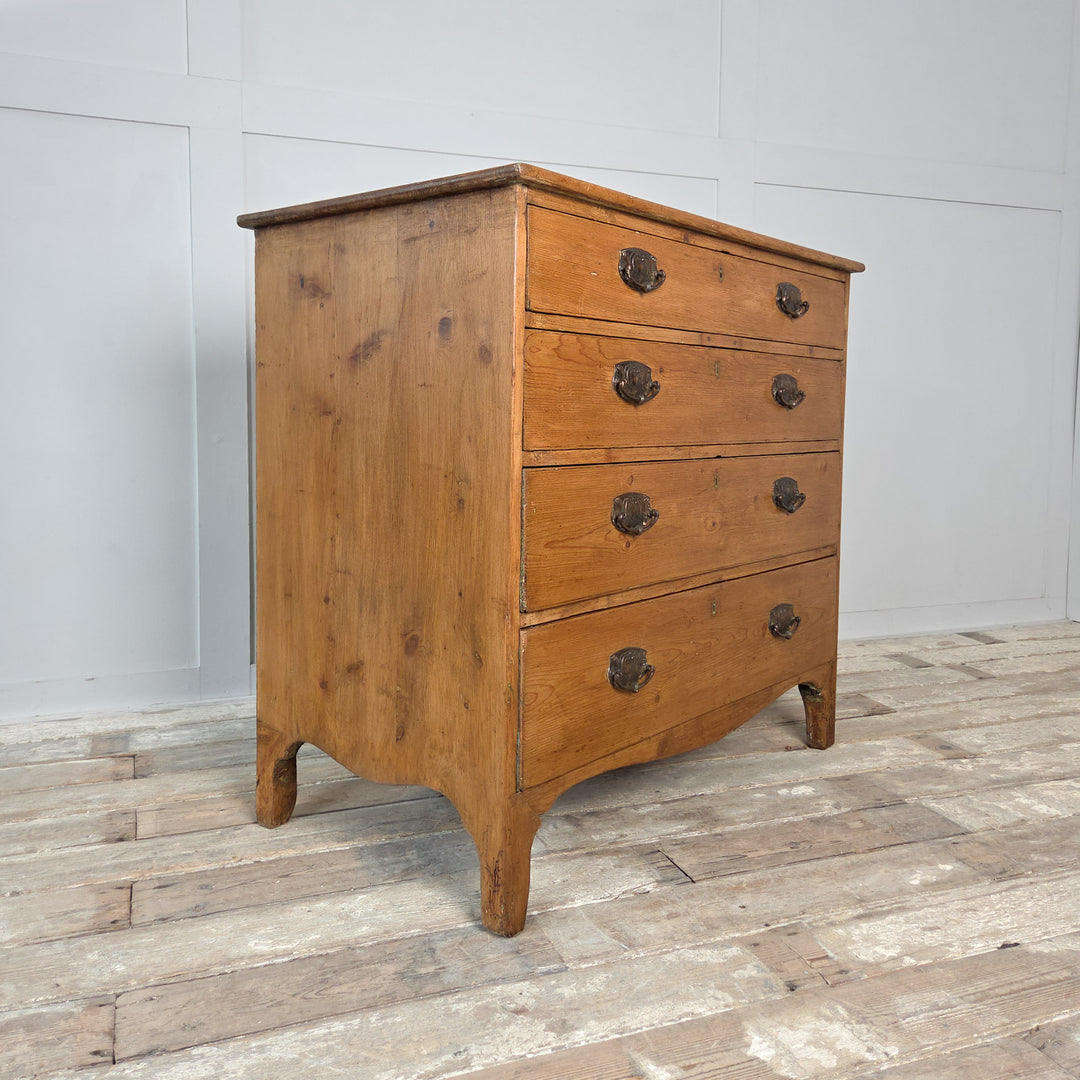 An early 19th-century Georgian pine chest of drawers with five drawers arranged two over three, featuring oval brass pull handles and shaped bracket feet. A fine example of antique country pine furniture, combining solid Georgian craftsmanship with practical storage.