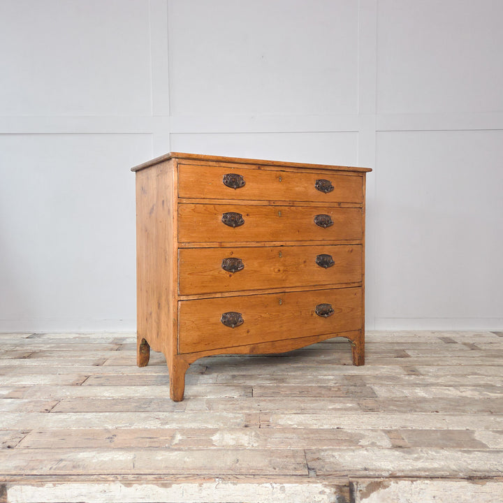 An antique Georgian pine chest of drawers in a two-over-three layout, with brass handles and shaped feet. A versatile country house furniture piece that suits bedroom, hallway or sitting room settings, adding warmth and authenticity to classic English interiors