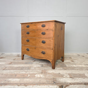 A 19th-century Georgian chest of drawers crafted from pine, with oval brass handles and a shaped apron. A timeless antique furniture piece for farmhouse-inspired spaces, perfect for use as bedroom storage or as a sideboard in a period home.