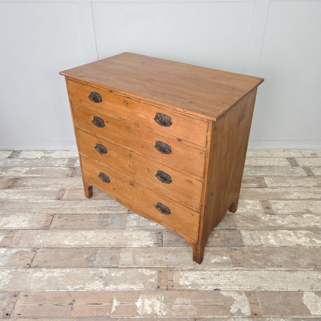An antique Georgian pine chest of drawers with a two-over-three drawer layout, brass hardware and shaped feet. A sturdy country pine furniture piece reflecting early 19th-century English design, built for both longevity and everyday use.