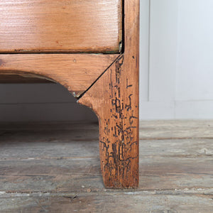 A Georgian pine chest of drawers from the early 19th century with brass pulls and shaped feet. A classic antique furniture piece made from solid English pine, combining function and understated Georgian design.