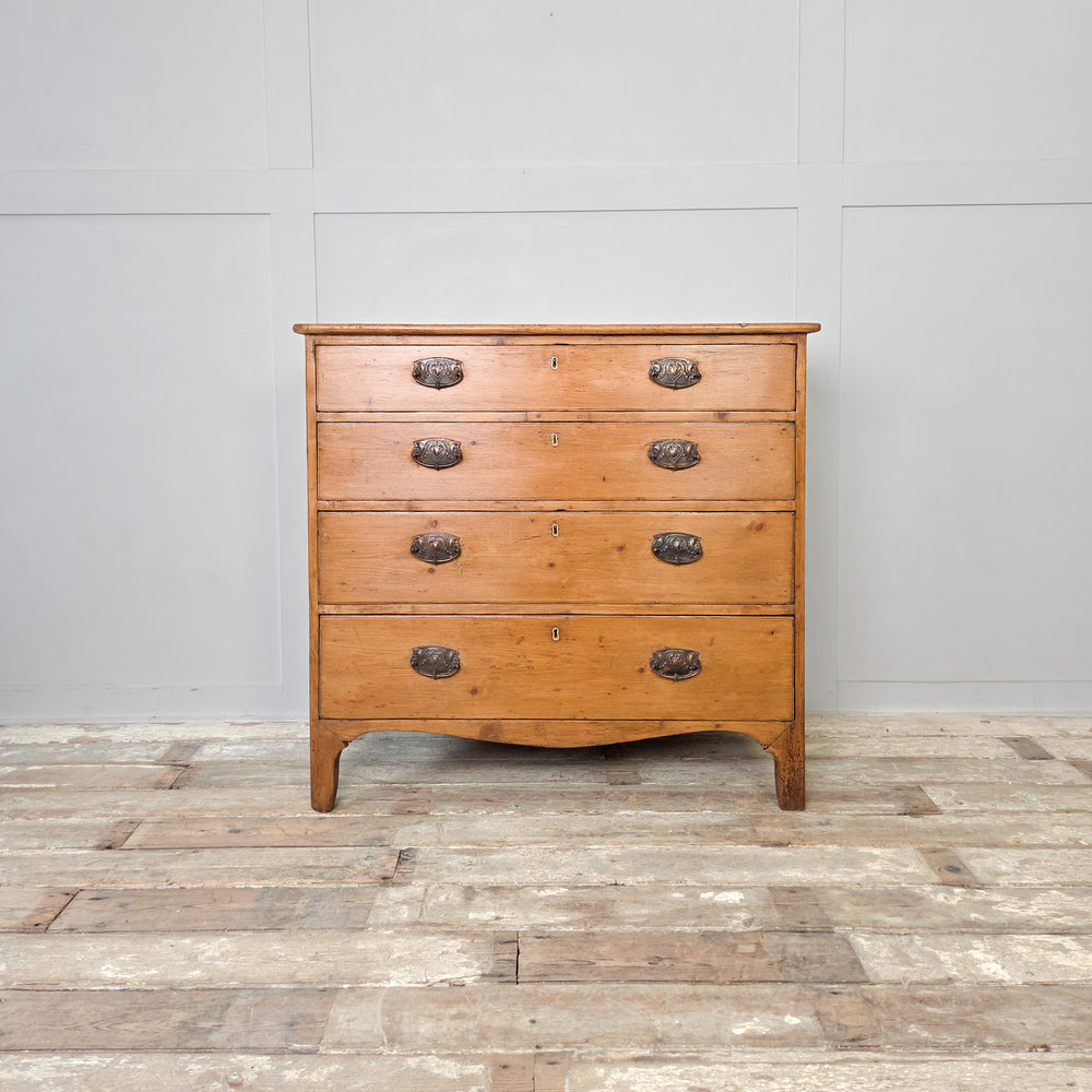 A Georgian pine chest of drawers from the early 1800s with five drawers, brass pulls and a shaped lower apron. A characterful piece of antique bedroom storage, ideal for traditional or rustic interiors, hallways or living rooms styled with antique pine furniture.
