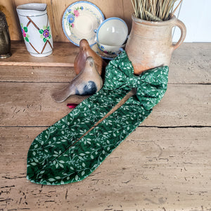 Decorative bow with festive design, brass ring, and velvet ribbon.
